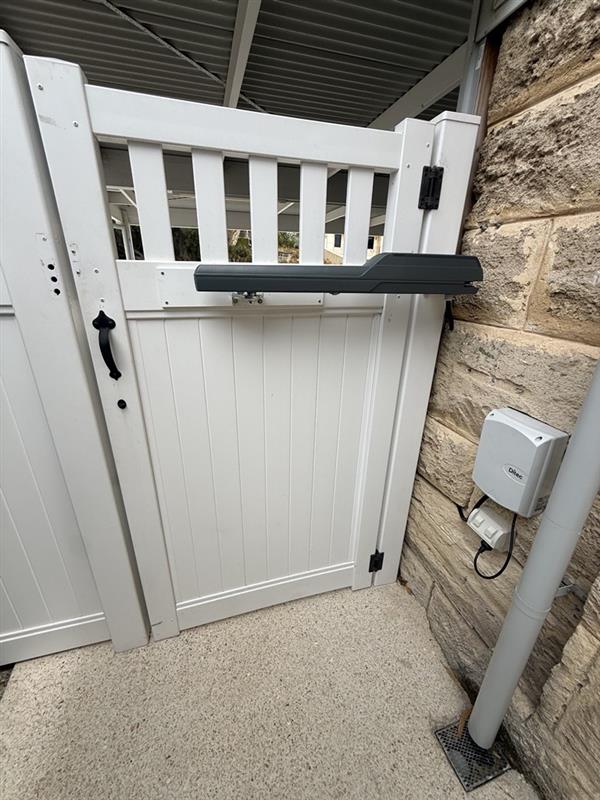 Automatic swing gate operator installed on a white residential gate
