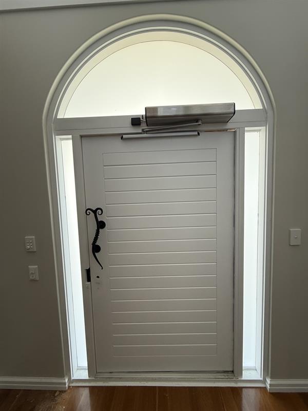 Commercial-grade automatic swing operator installed on a residential entry door